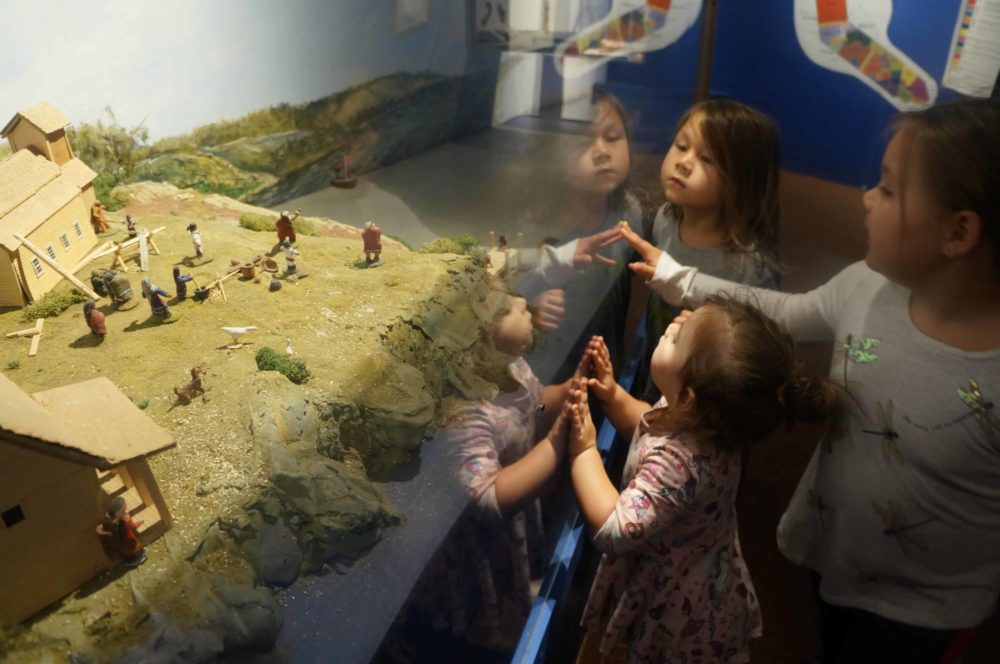 Three children viewing indigenous art piece