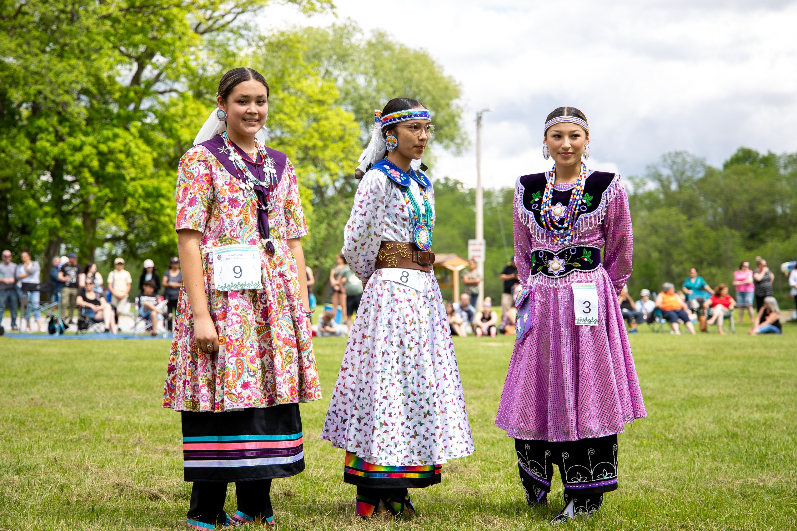 Three indigenous women traditionally dressed standing in the grass