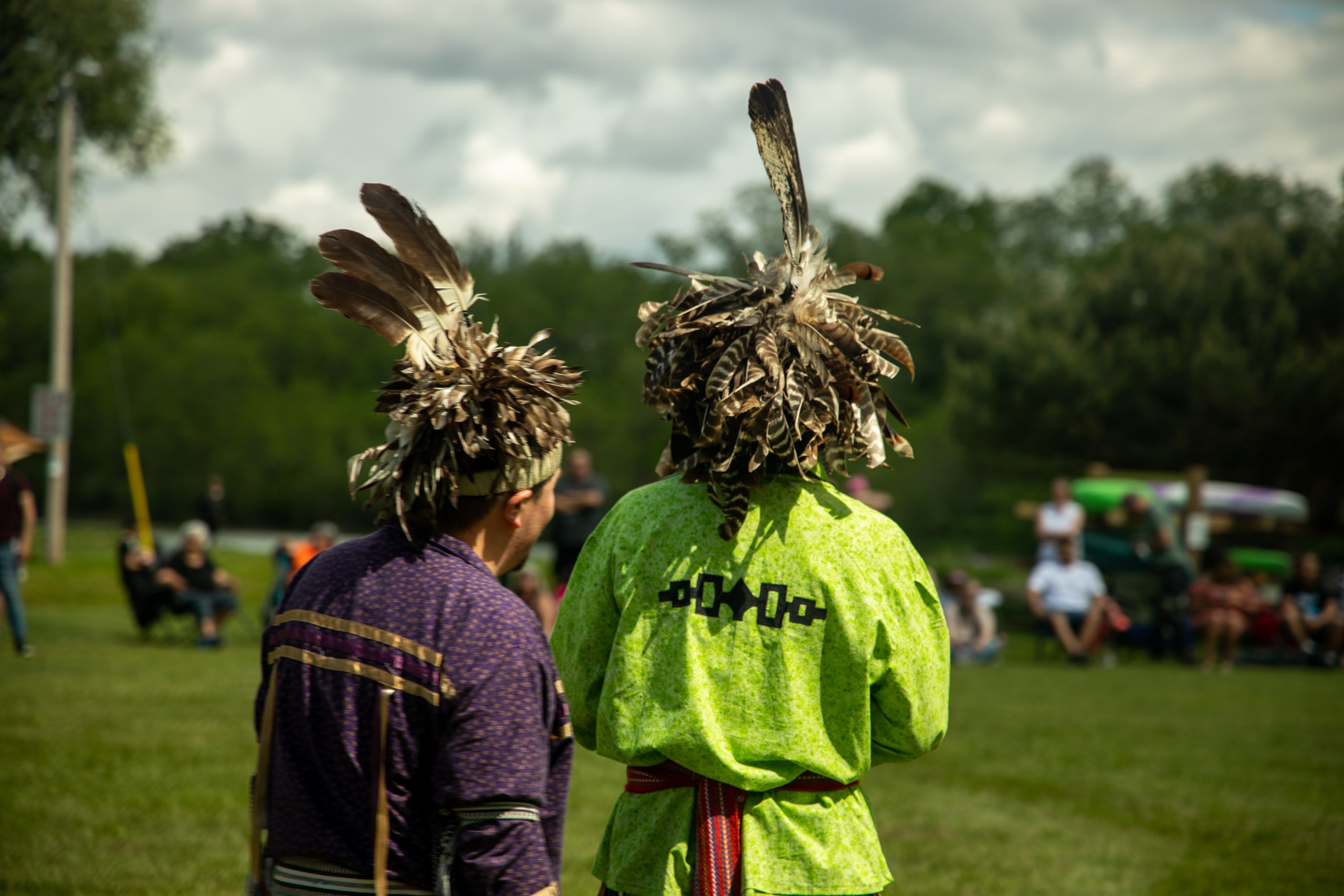 Two indigenous people in feathered headdress' staring off into the distance