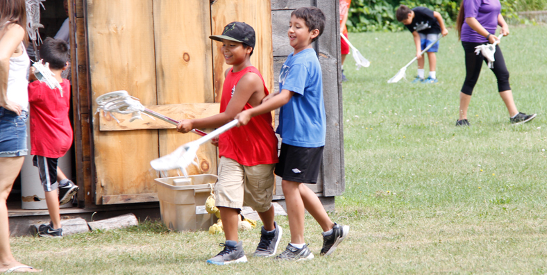 Two young boys holding lacrosse sticks