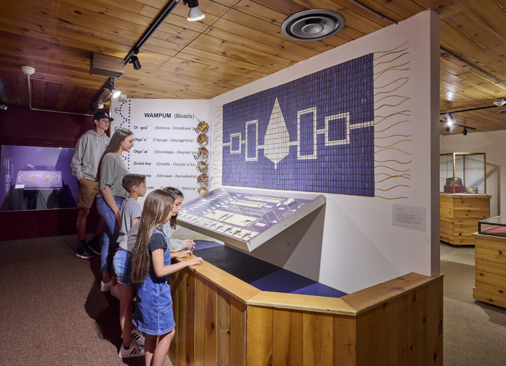 Woman observing indigenous artifacts through enclosed class case